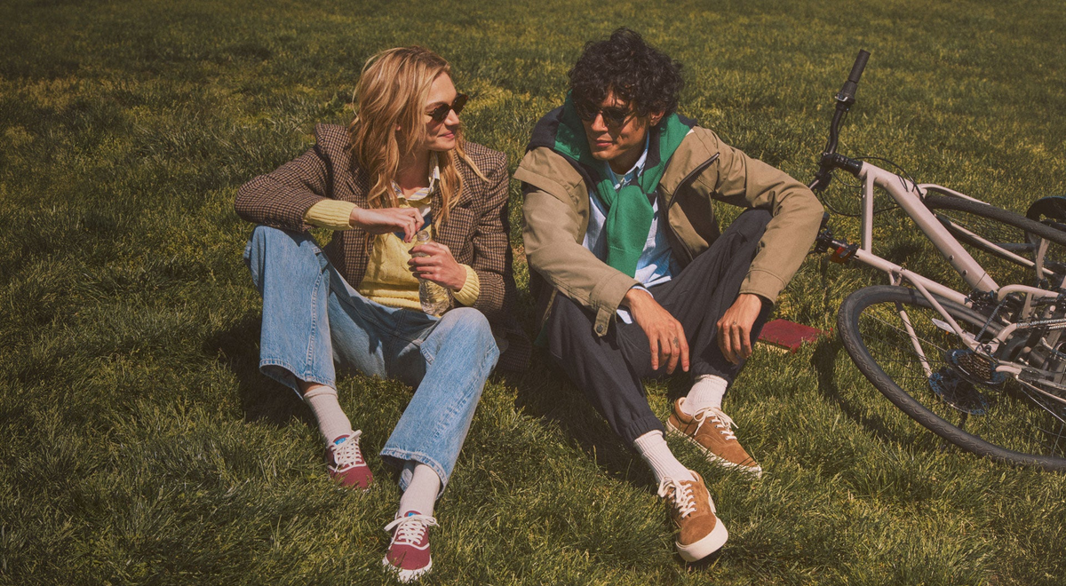 A man and a woman sitting on the grass next to a bicycle