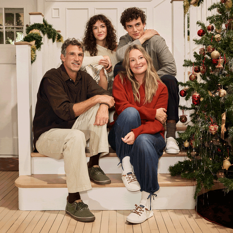 Animated GIF of a family of four on the stairs by a Christmas tree, shifting from all looking aside to the parents facing each other while the siblings look at the camera.