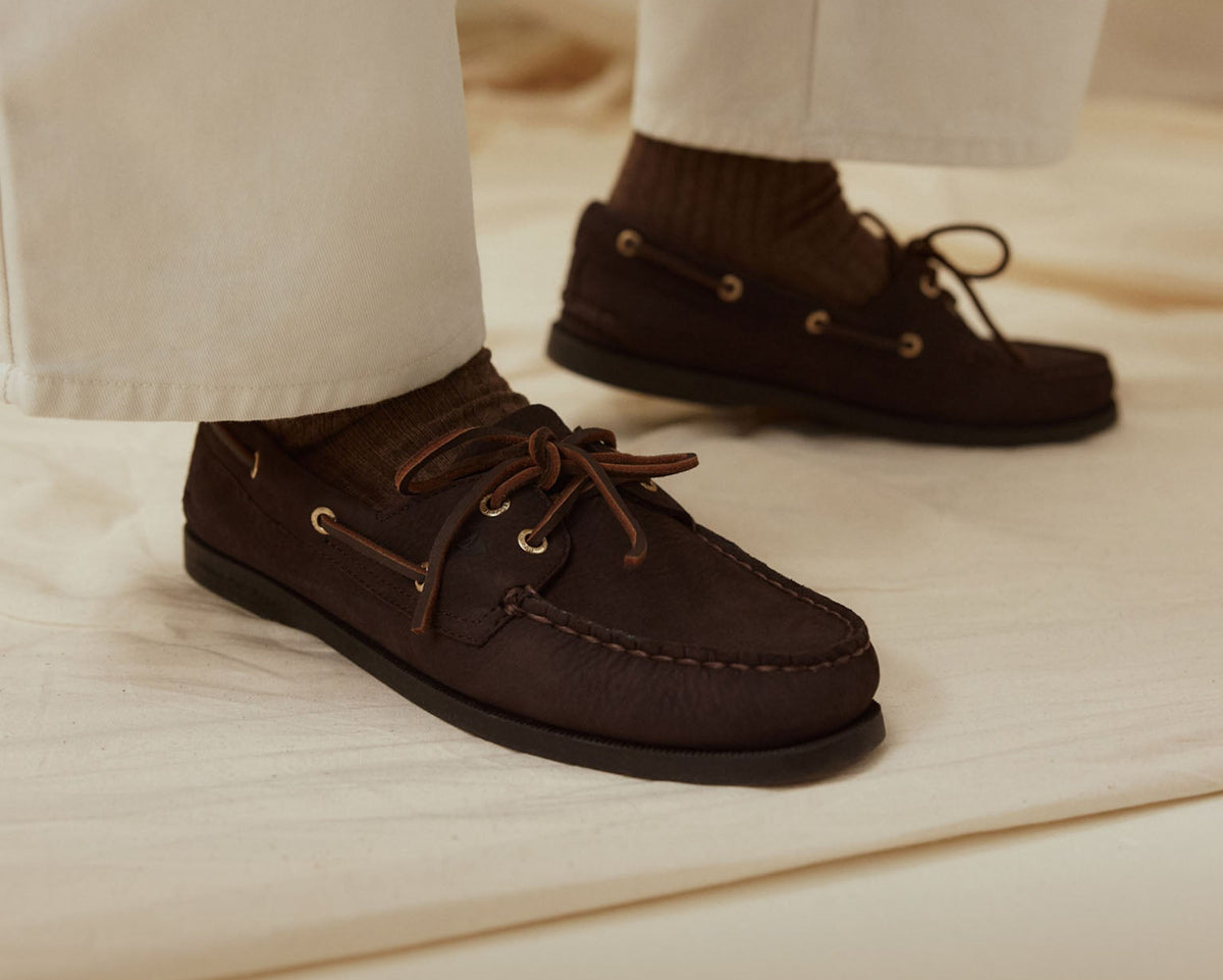 A pair of women's dark brown boat shoes with white pants
