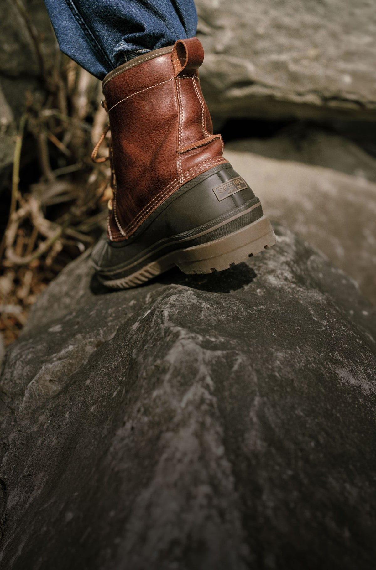 A man's burgundy boot on a rock