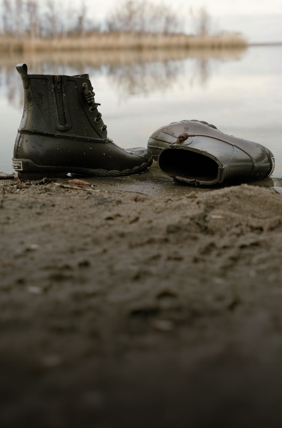 A pair of brown rubber duck boots by the water