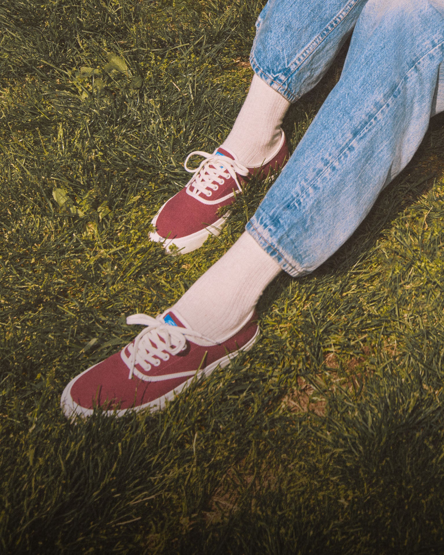 A woman sitting in the grass wearing red sneakers