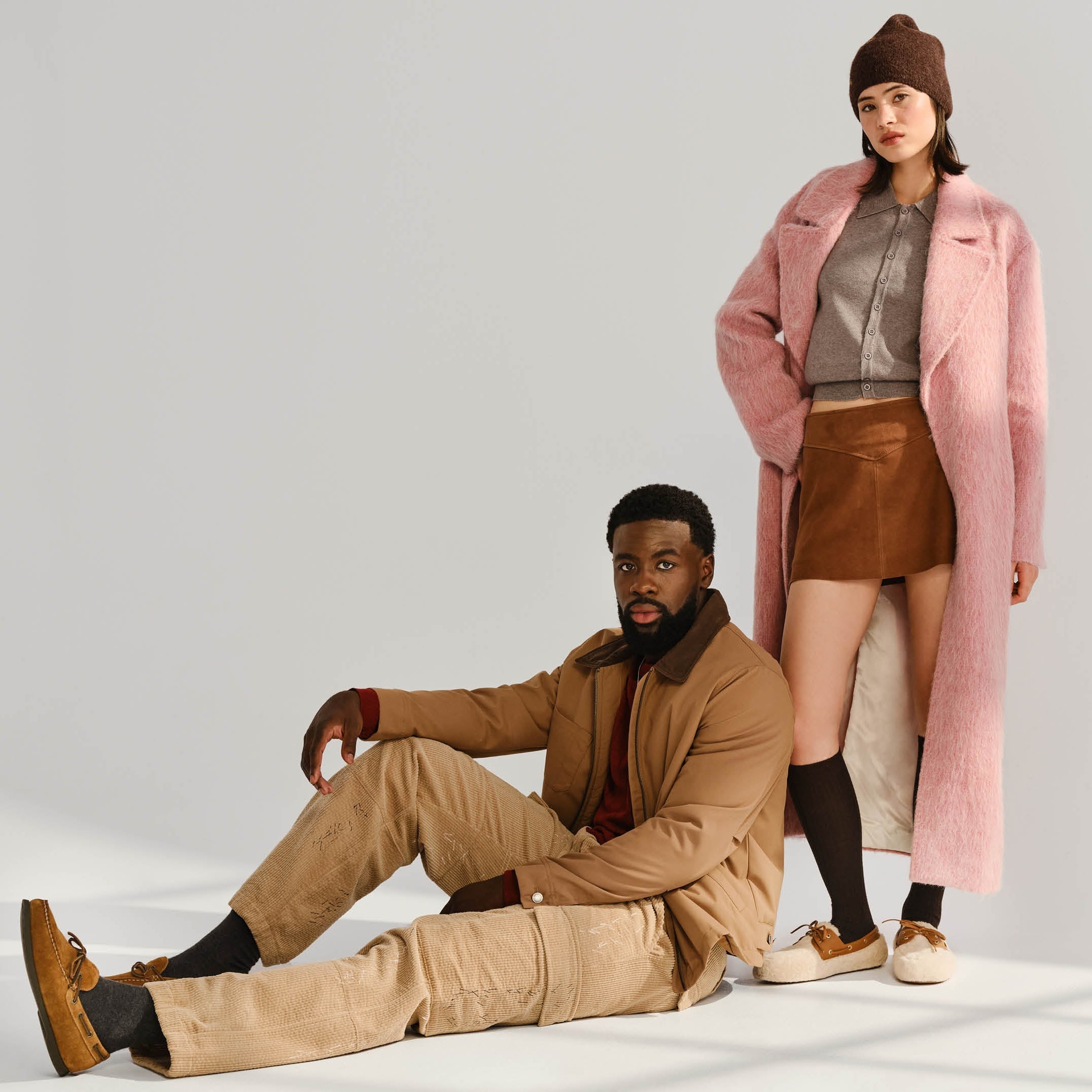 Two people wearing winter clothing on a white background